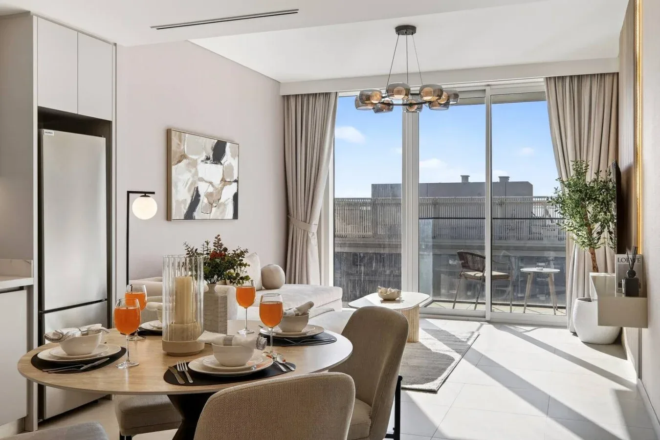 Un comedor luminoso se abre a un balcón a través de grandes ventanales.