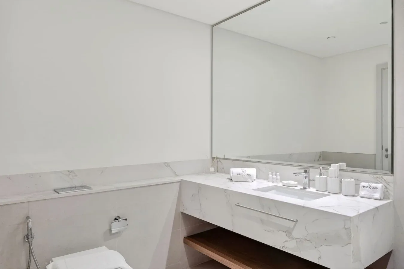 Un baño luminoso con un amplio espejo sobre un tocador de mármol.