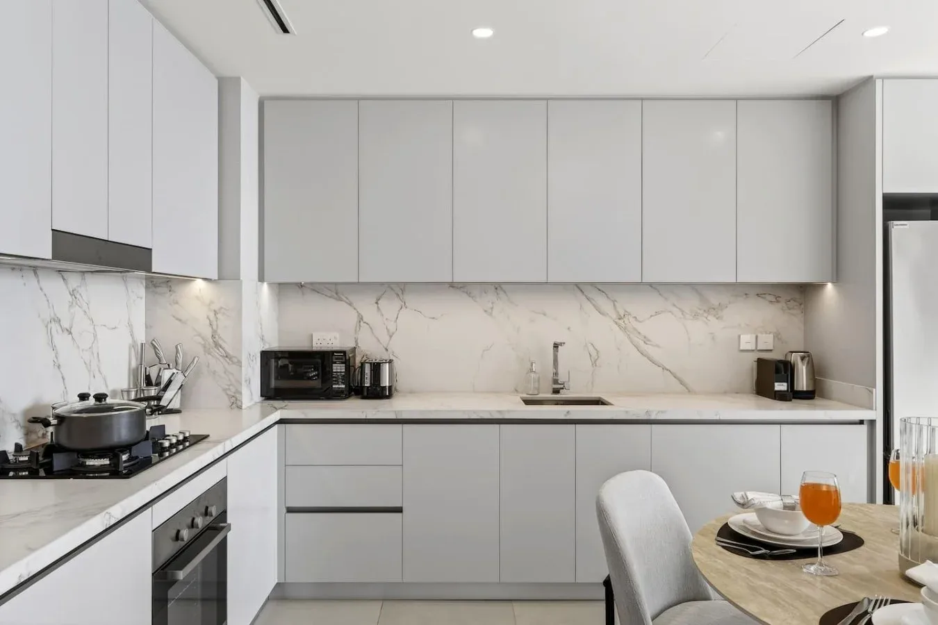 Una cocina moderna con gabinetes claros, un salpicadero veteado y una mesa de comedor.