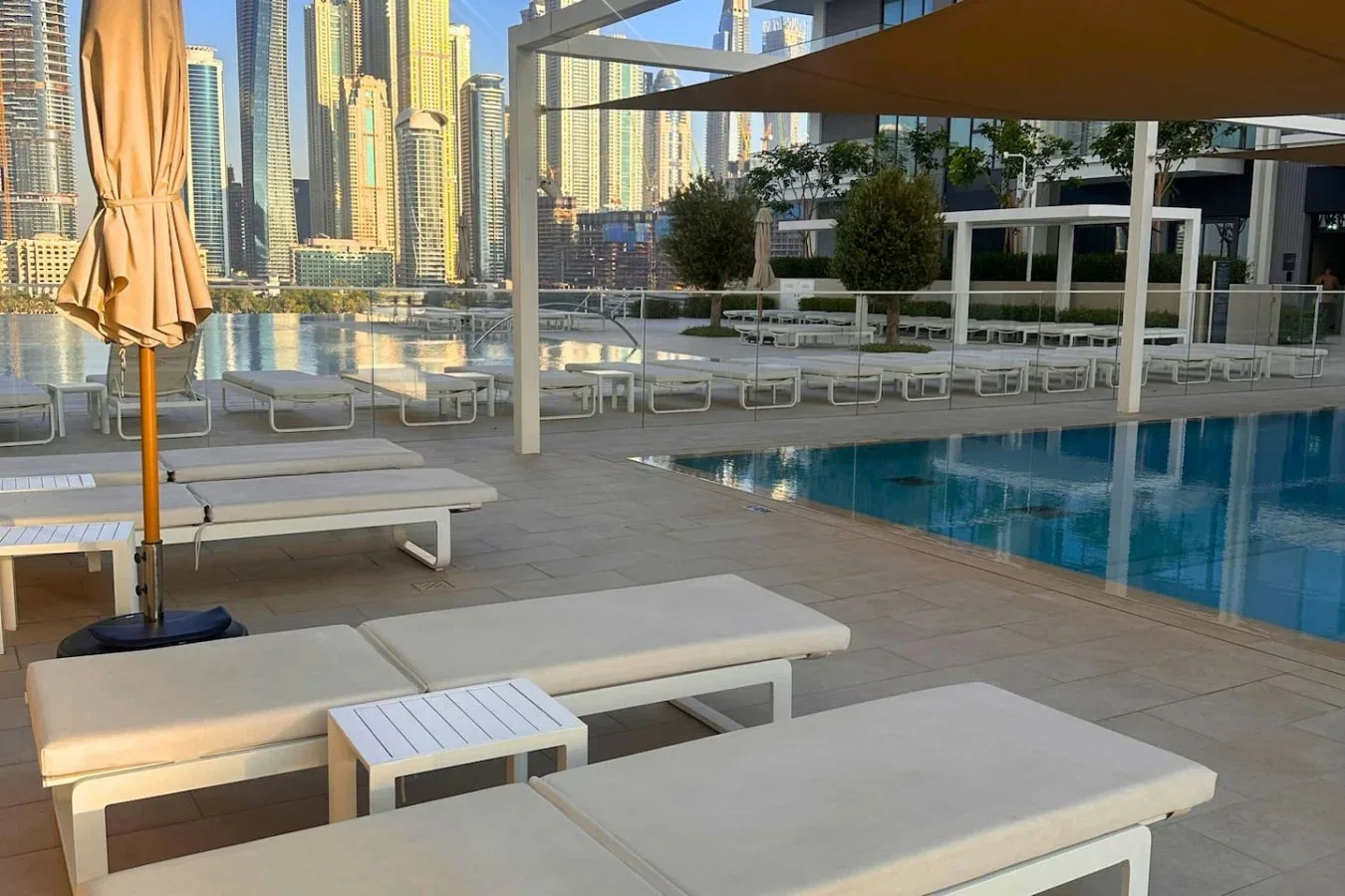 Una terraza con piscina y asientos de descanso, con edificios altos al fondo.