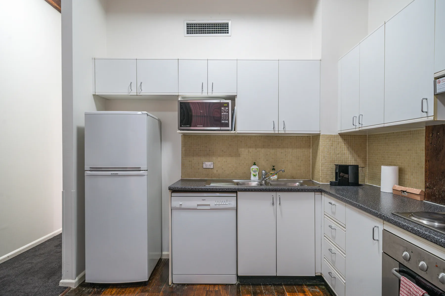 A compact kitchen with white cabinets, a refrigerator, and a countertop.