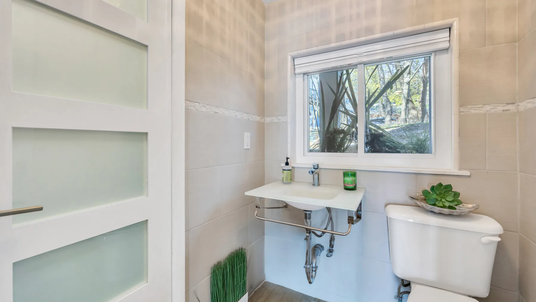 Un baño con lavabo suspendido, inodoro y ventana.