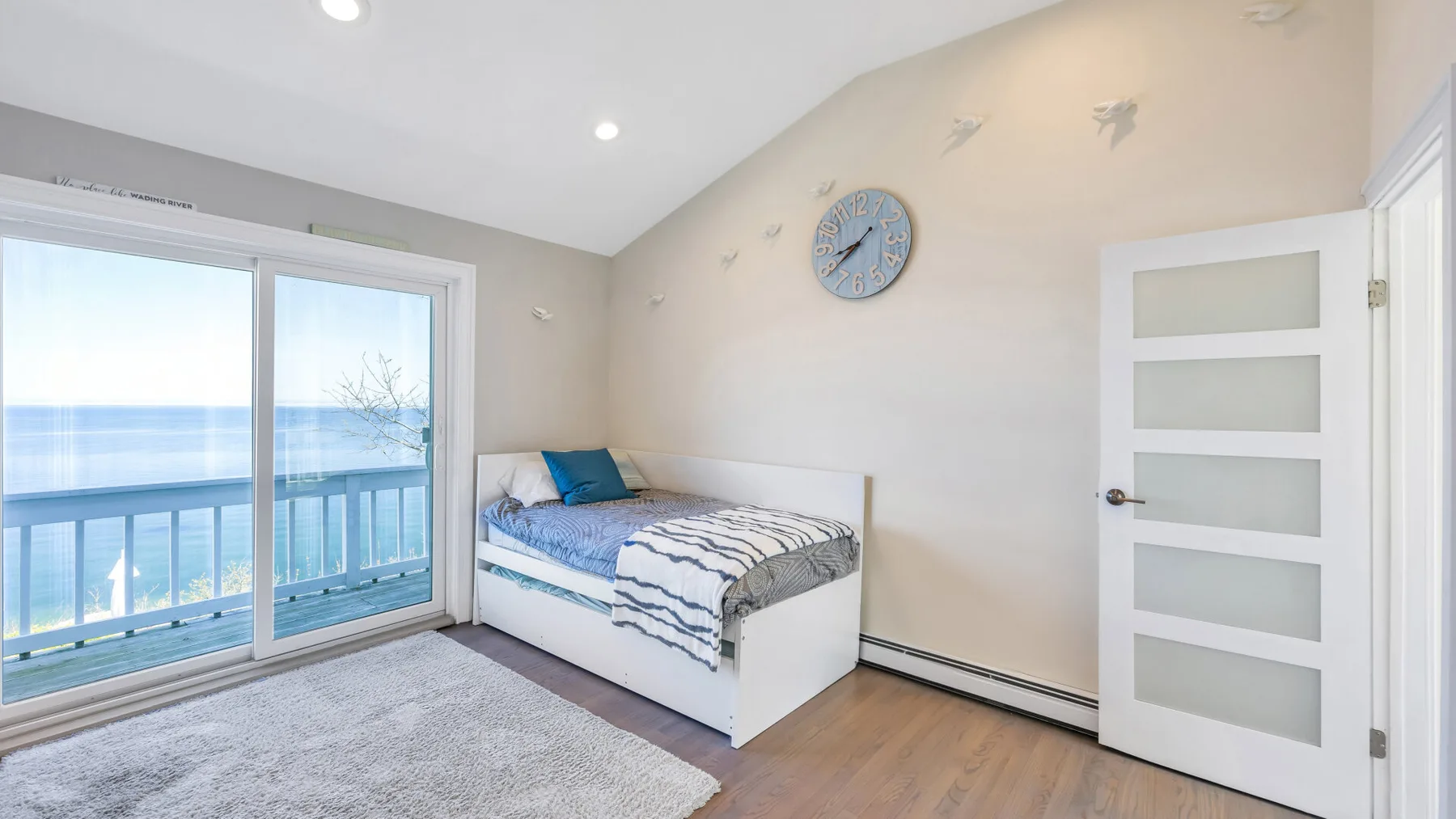 Un dormitorio luminoso con una cama junto a puertas corredizas de vidrio con vistas al agua.