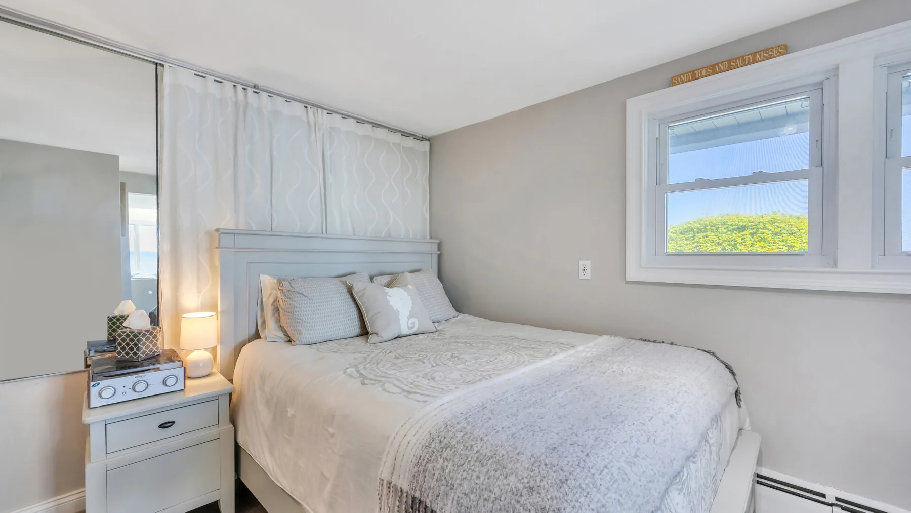 Un dormitorio con una cama junto a una ventana y una mesita de noche.