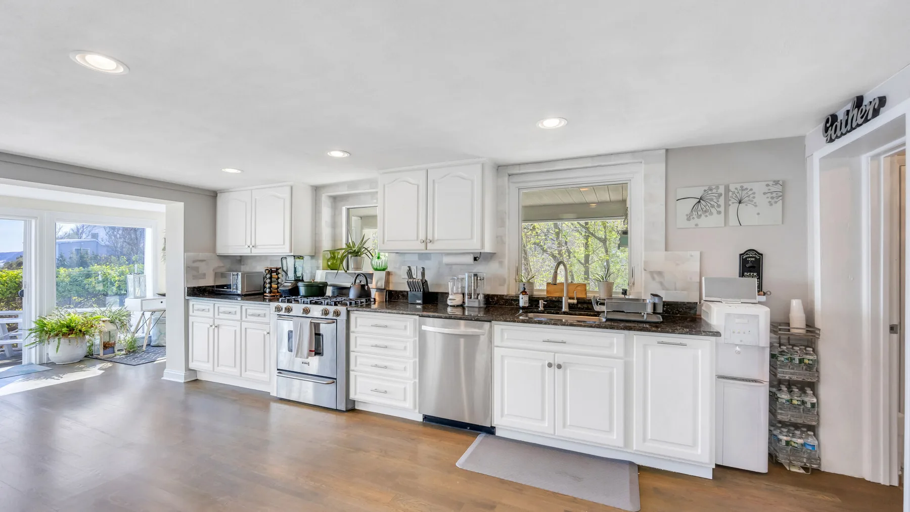 Una cocina luminosa con gabinetes blancos, encimeras oscuras y una ventana amplia.
