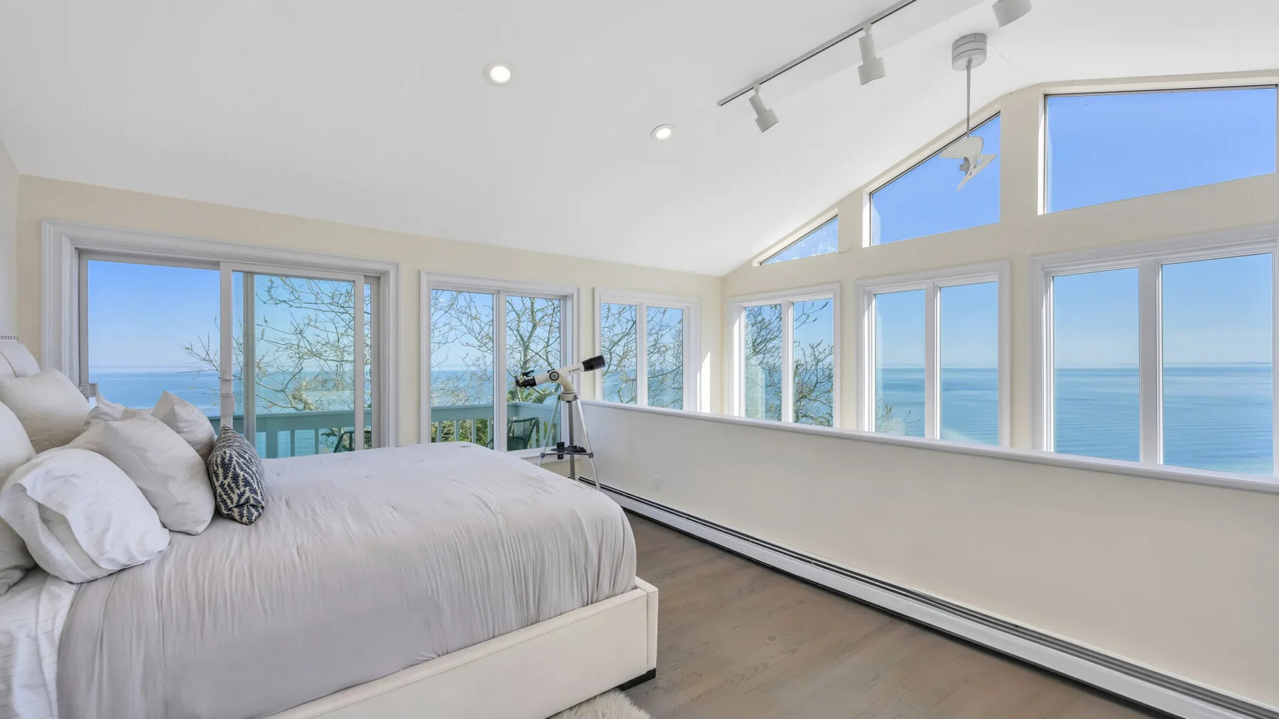 Un dormitorio luminoso con una cama junto a grandes ventanas con vistas al mar.