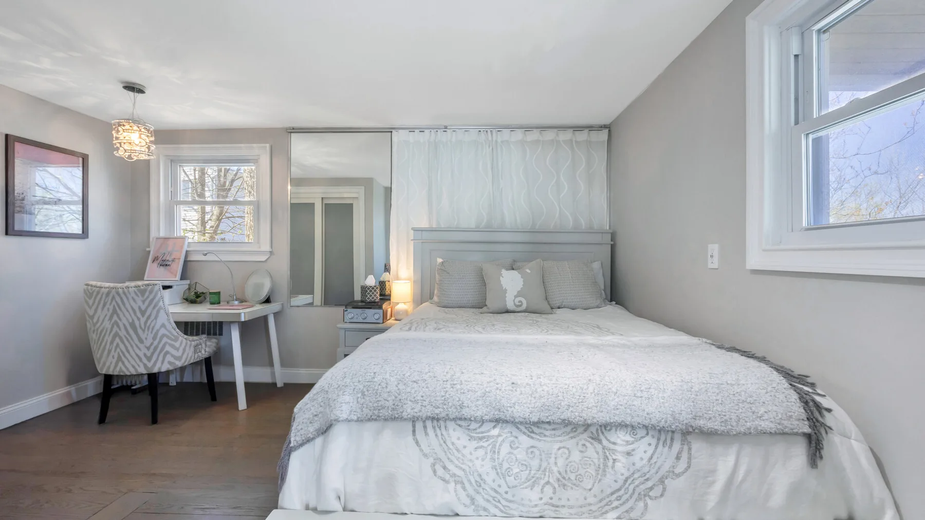 Un dormitorio con una cama, un escritorio pequeño y ventanas.