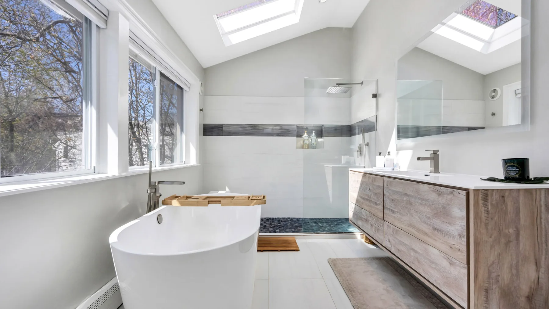 Un baño luminoso con bañera exenta, ducha de cristal y tragaluces.