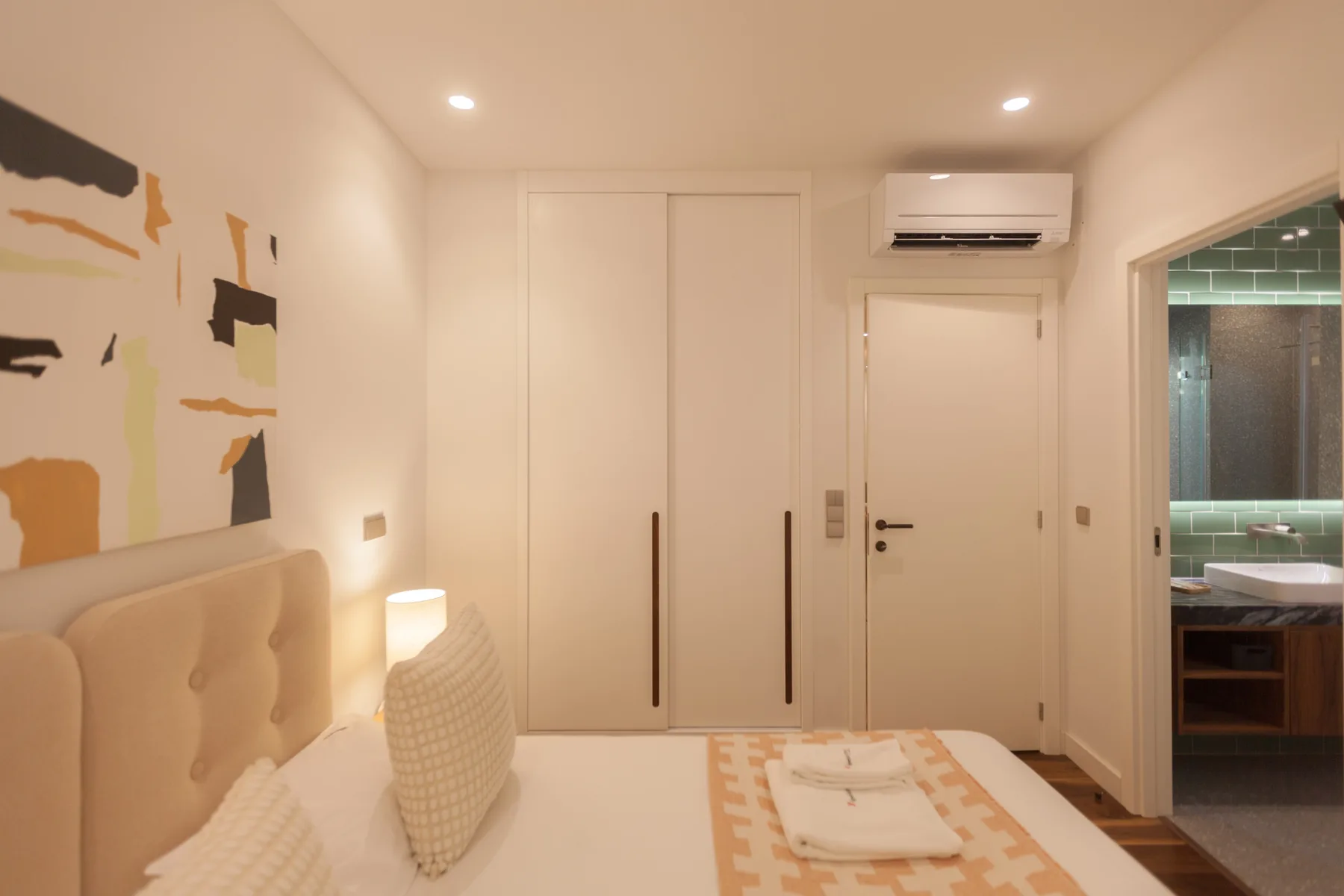 Dormitorio con una cama, armarios empotrados y un baño visible a través de la puerta.