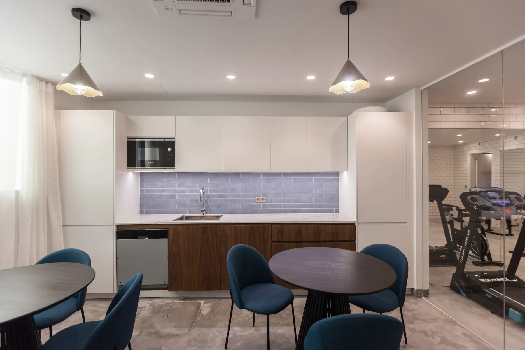 Una cocina moderna con zona de comedor, asientos azules y salpicadero de azulejos.