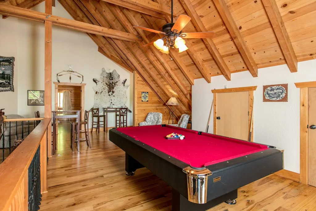 Una sala de juegos tiene una mesa de billar bajo un techo abovedado de madera.