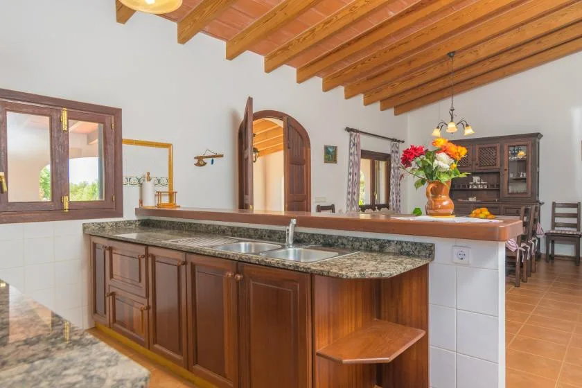 Una cocina con una encimera larga y vigas de madera en el techo.