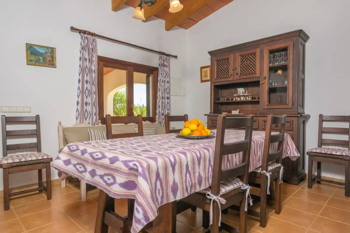 Un comedor con una mesa bajo vigas de madera vistas.