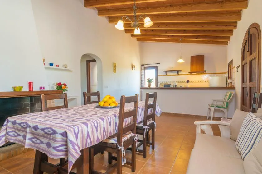Comedor con una mesa larga y una barra de cocina al fondo.