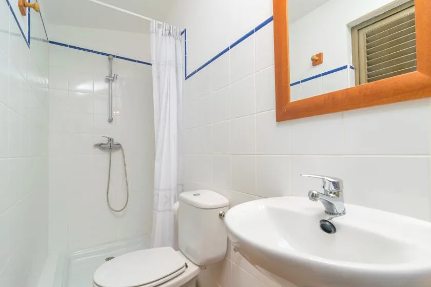 Un baño alicatado con ducha, inodoro y lavabo.