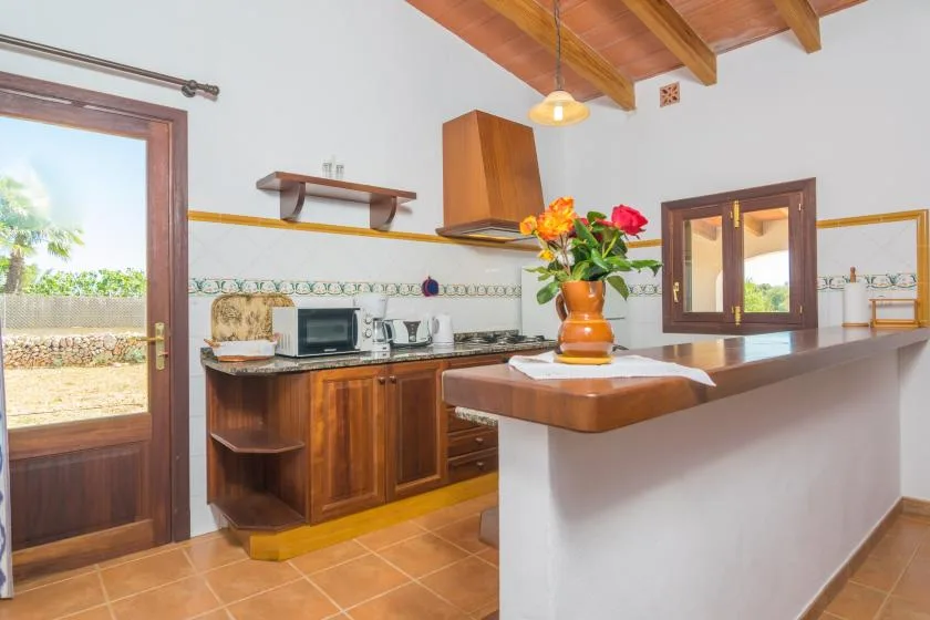 Una cocina luminosa con gabinetes de madera, una encimera y un jarrón con flores.