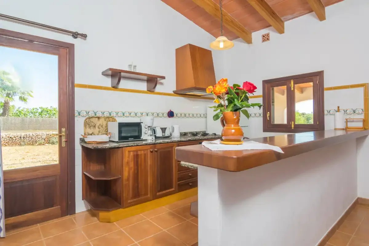Una cocina luminosa con armarios de madera, una encimera de azulejos y flores en la isla.