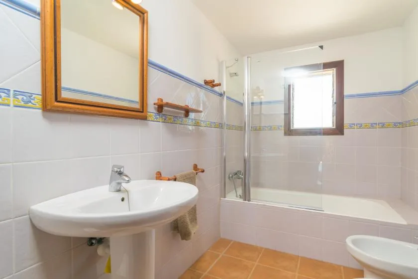 Un baño alicatado con lavabo, bañera y ventana.