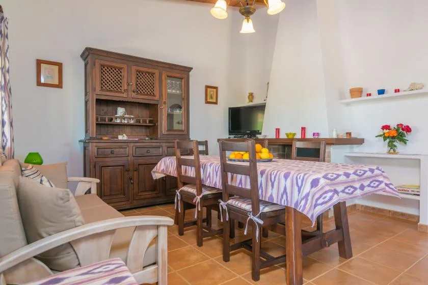 Un comedor con una mesa larga, sillas de madera y un armario alto.