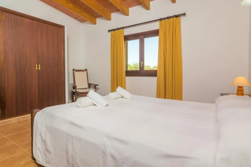 Un dormitorio con una cama grande, una ventana y cortinas mostaza.