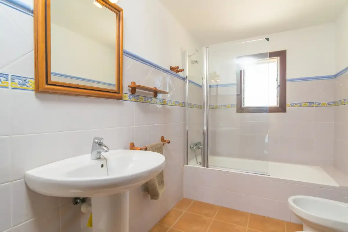 Un baño con azulejos, bañera, lavabo y ventana.