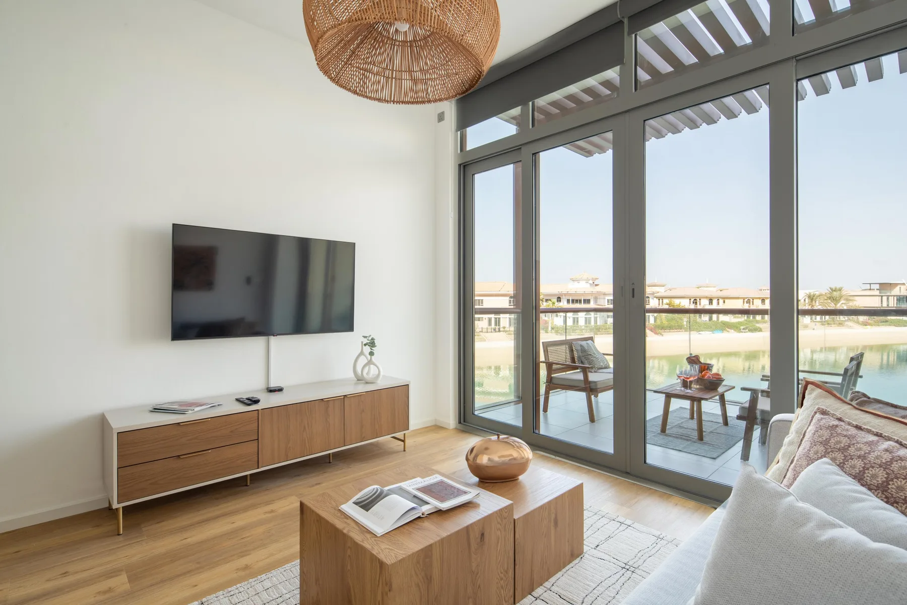 A bright living room opens through glass doors to a patio with seating.