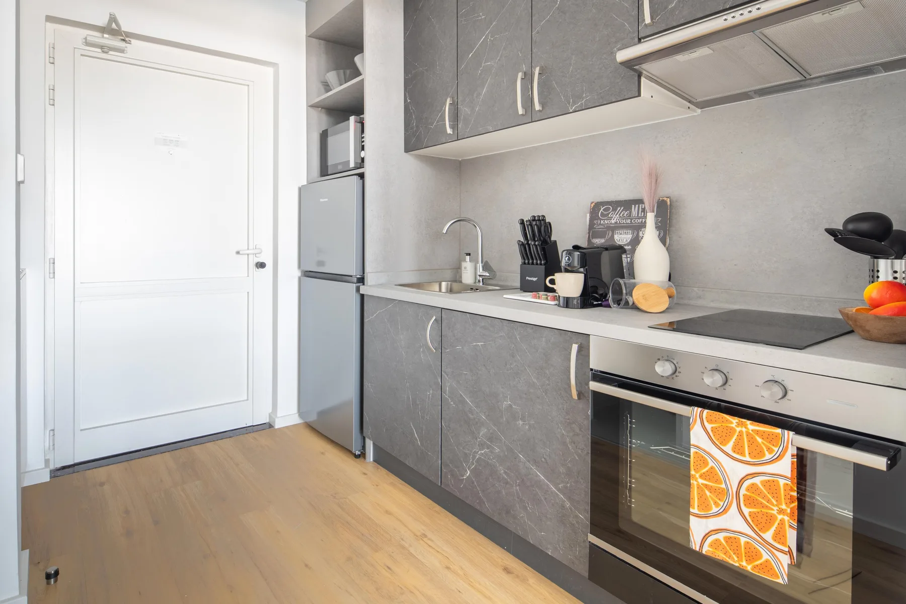 A compact kitchen with gray cabinets, a countertop, and an oven.