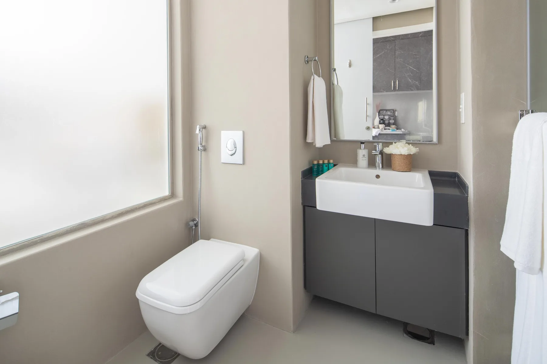 A modern bathroom with a wall-mounted toilet and a vanity sink.
