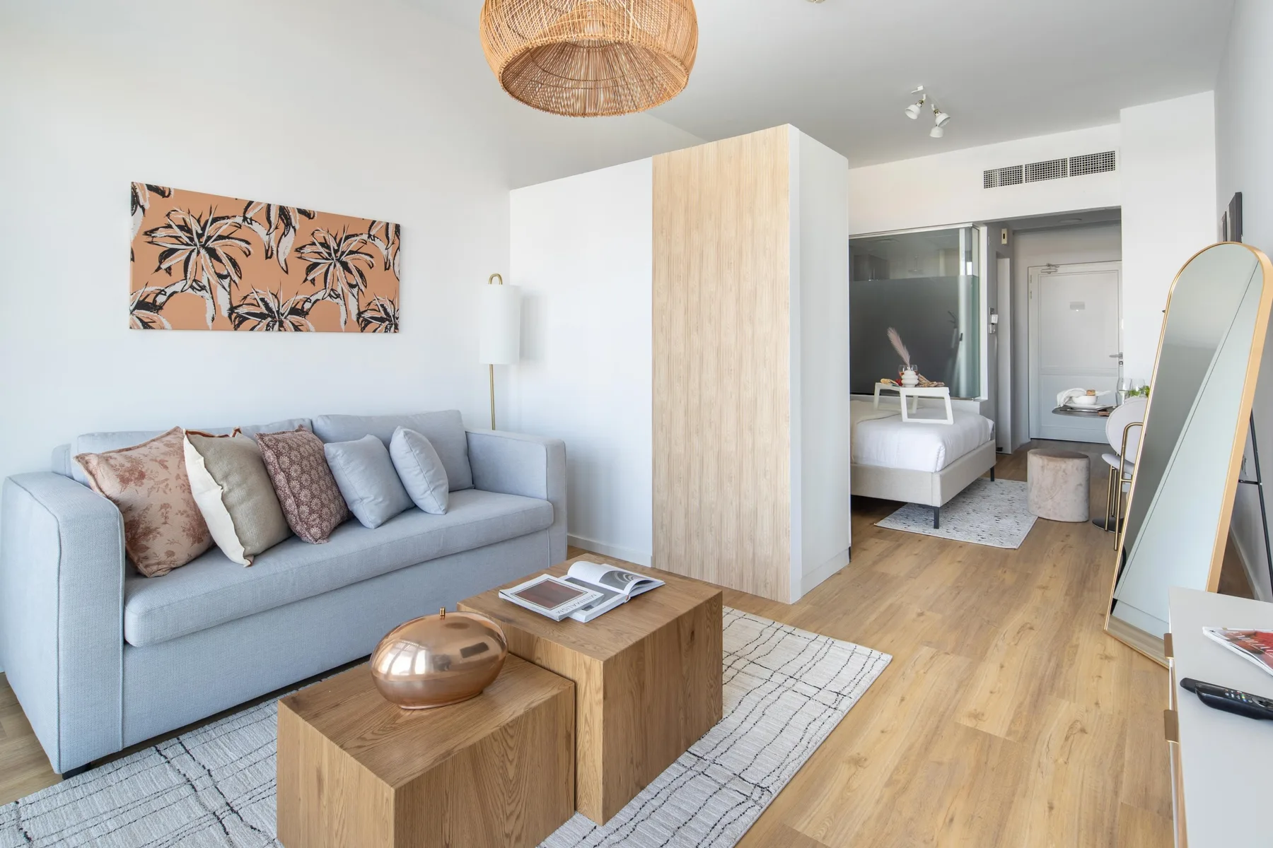 A bright bedroom sitting area with a gray sofa and wooden coffee tables.
