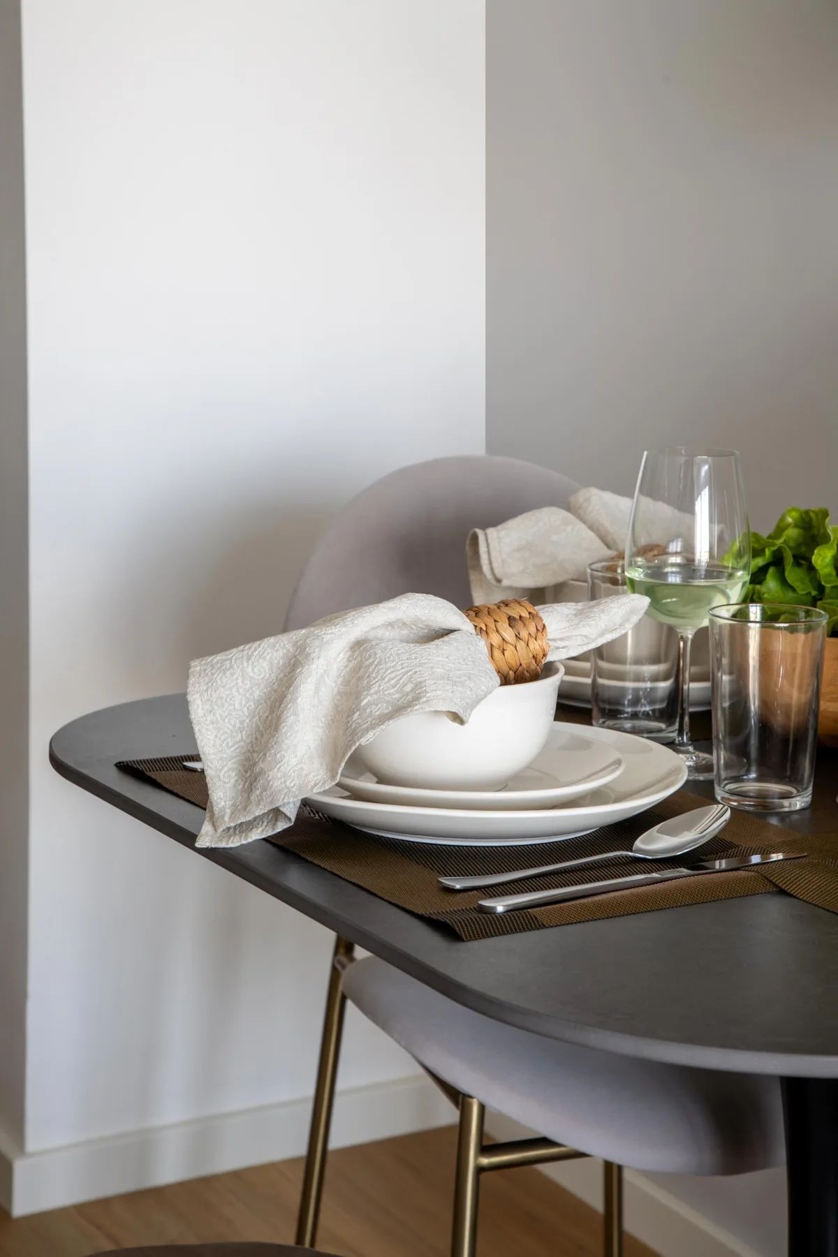 A dining table is set with plates, glassware, and folded cloth napkins.