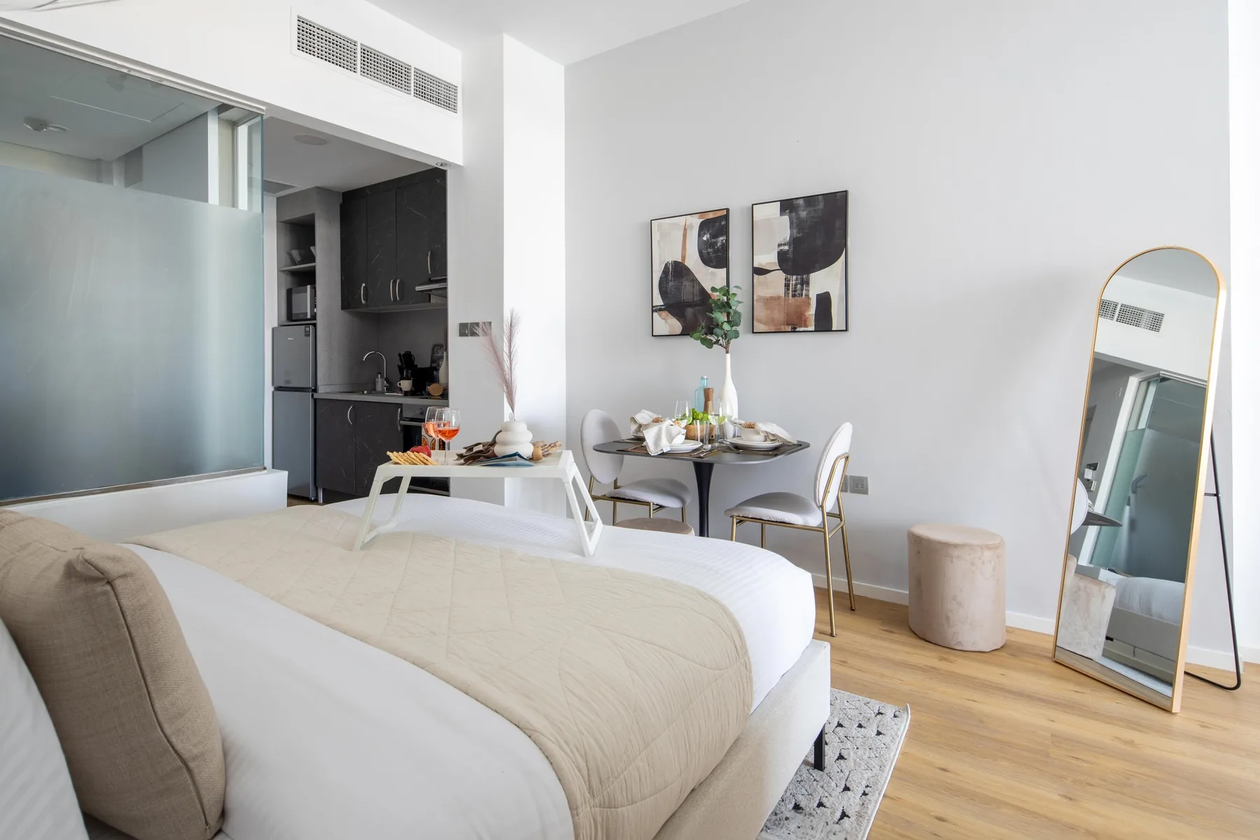 A bright bedroom with a bed, a small dining area, and a compact kitchenette.