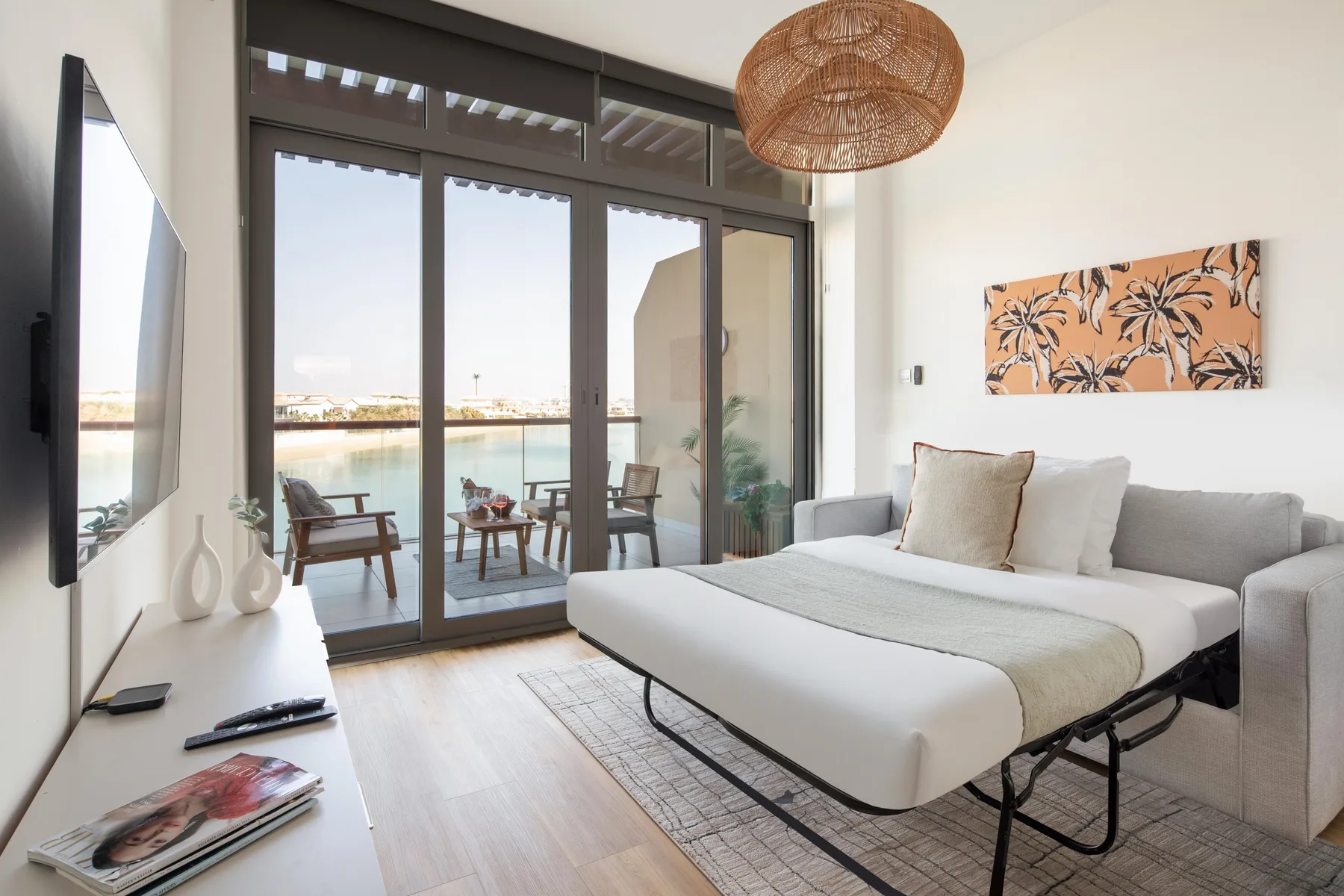 A bright living room with seating beside large windows overlooking the water.