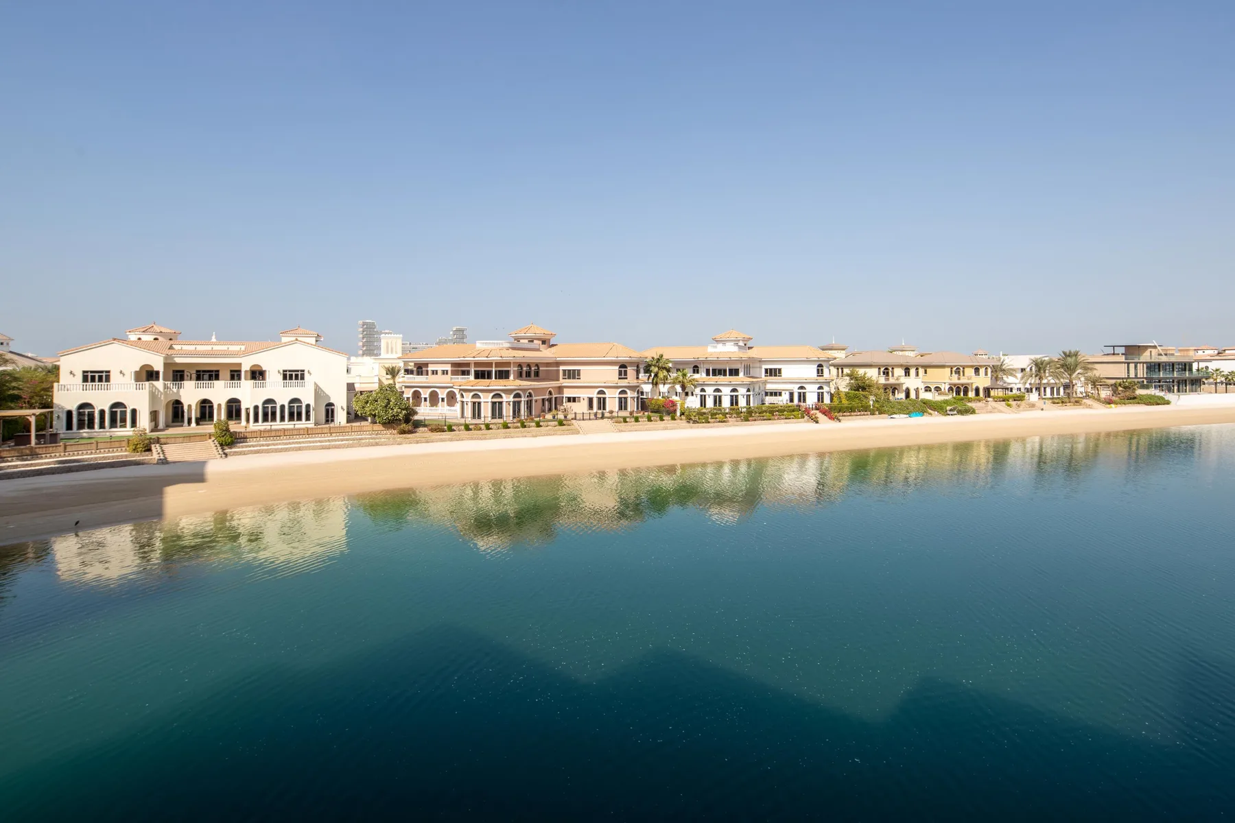 A waterfront complex of low-rise buildings lines a calm lagoon.