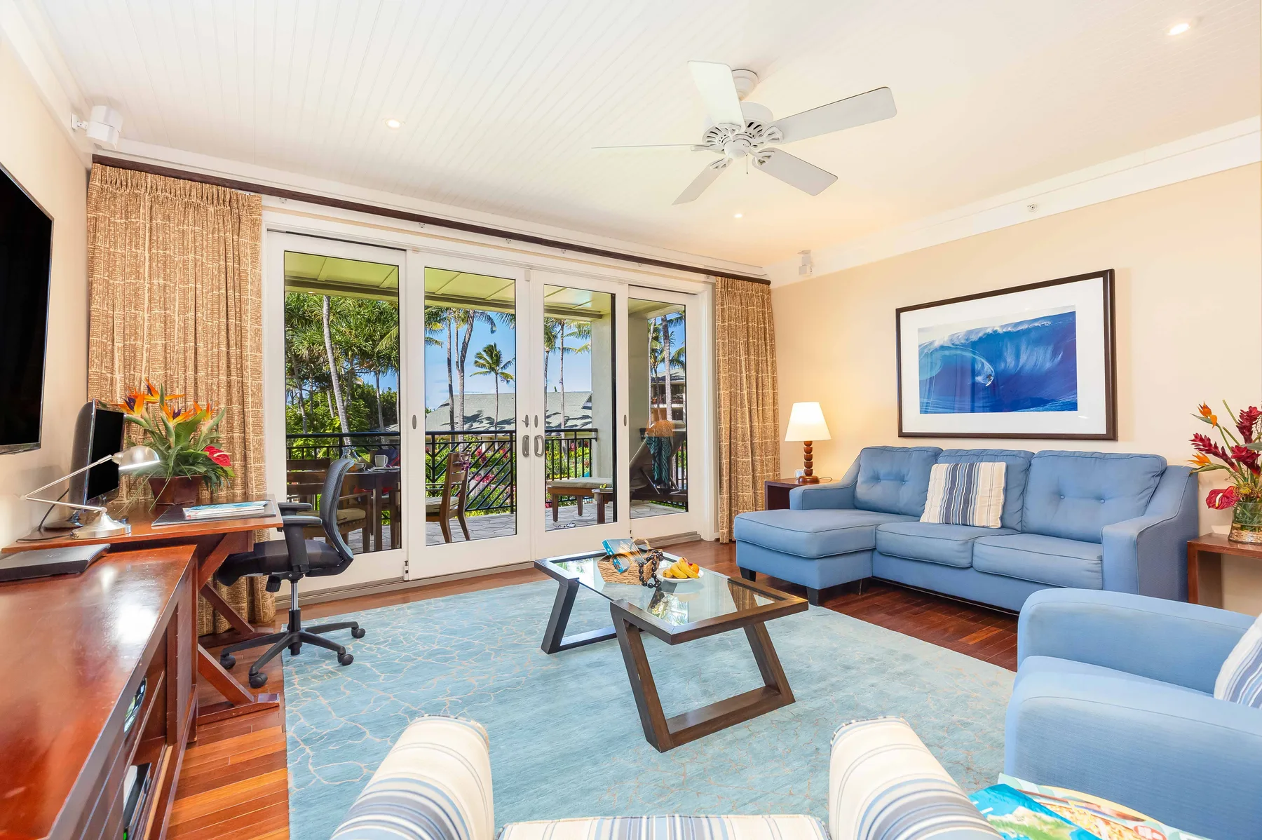 A living room with a blue seating area and glass doors opening to a balcony.