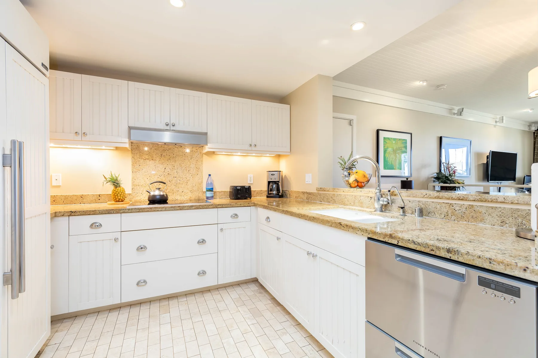 A bright kitchen with white cabinets, stone countertops, and stainless steel appliances.