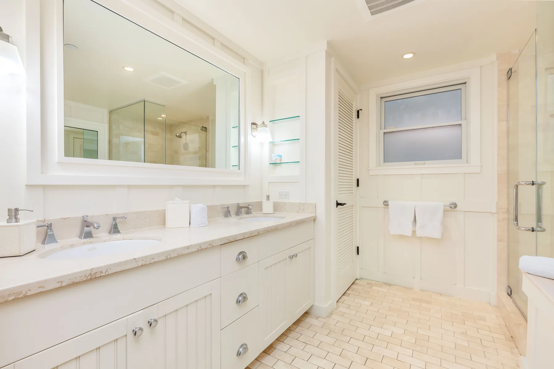 A bright bathroom with a long vanity, wall mirror, and shower.