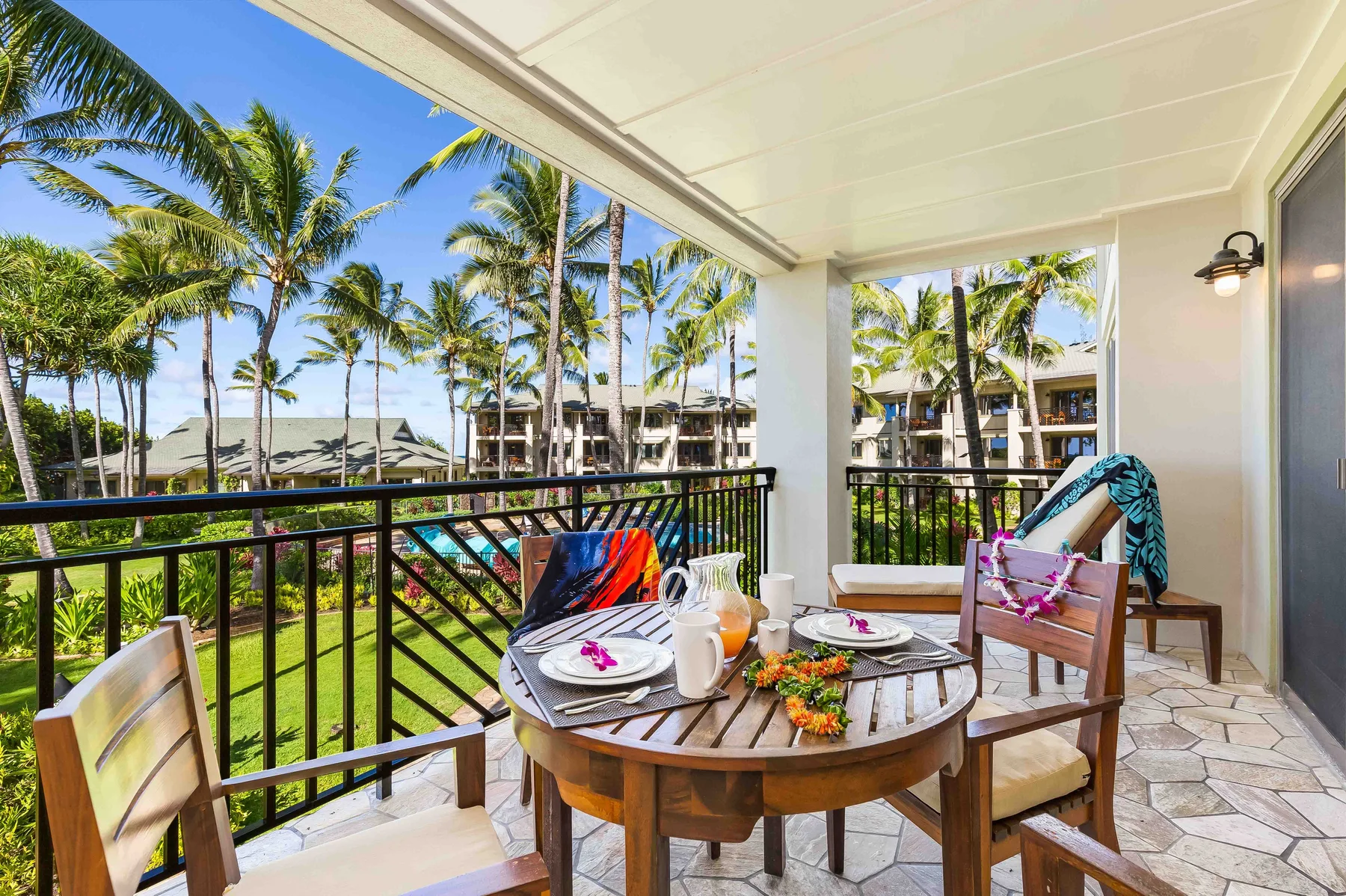 A covered outdoor dining area overlooks palm trees and landscaped grounds.