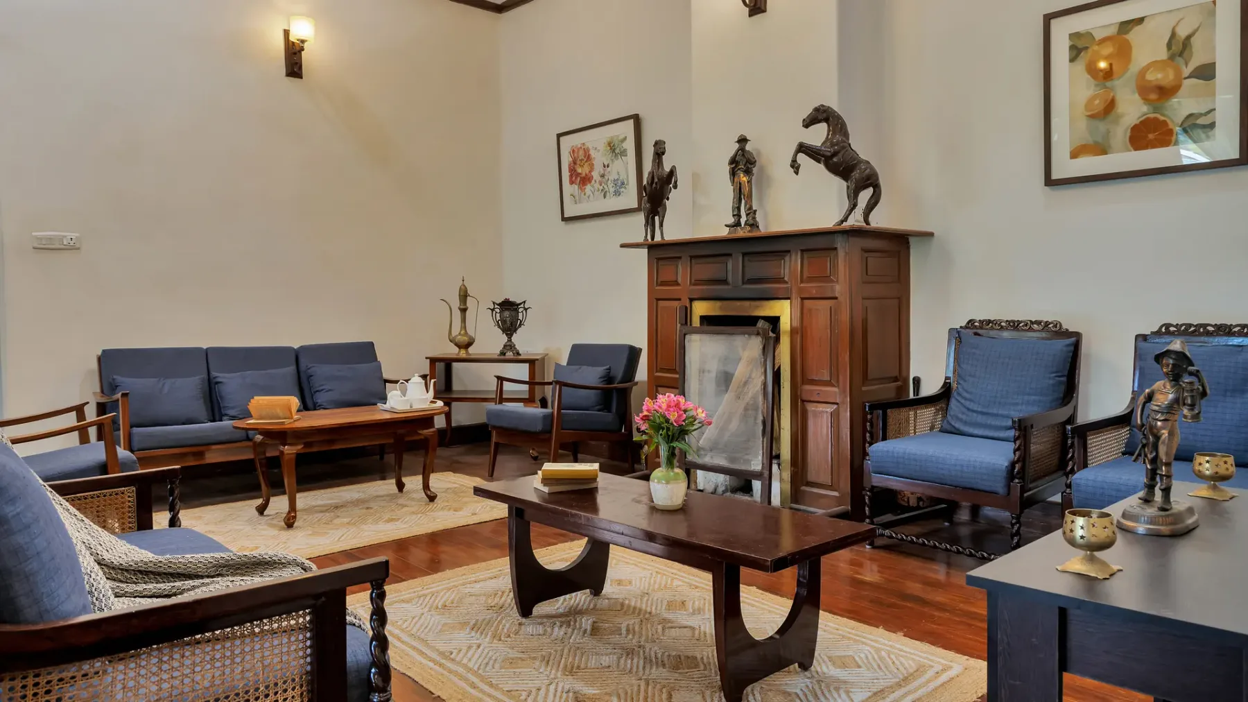 Una sala de estar con asientos, una chimenea y cuadros enmarcados.