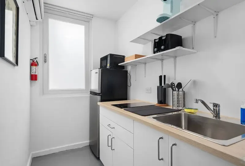 Cocina pequeña con placa de inducción, microondas, mininevera y fregadero
