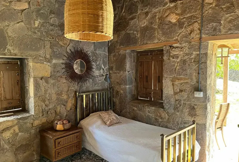 A bedroom with a single bed set against rustic stone walls.