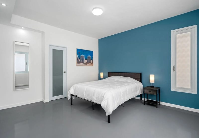 Dormitorio con cama king, aire acondicionado tipo split y arte con temática de playa