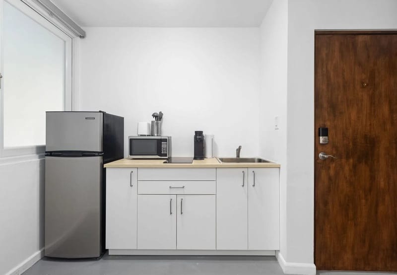 Cocina pequeña: nevera, microondas, cafetera y fregadero
