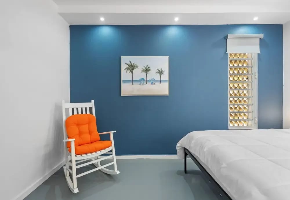 Queen bedroom with rocking chair and beach art