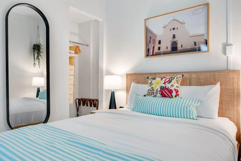 A tranquil sleeping area with decorative artwork and a generous mirror.