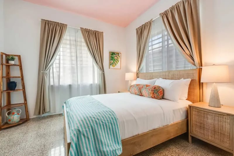 A bedroom with a queen-size bed dressed in white linens and a light blue throw.