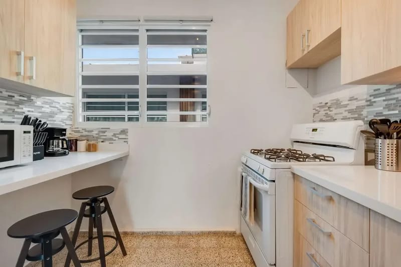 A narrow galley kitchen with a gas stove, oven and refrigerator.