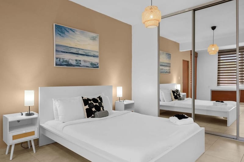 Dormitorio con una cama doble, armario con espejo y ventana.